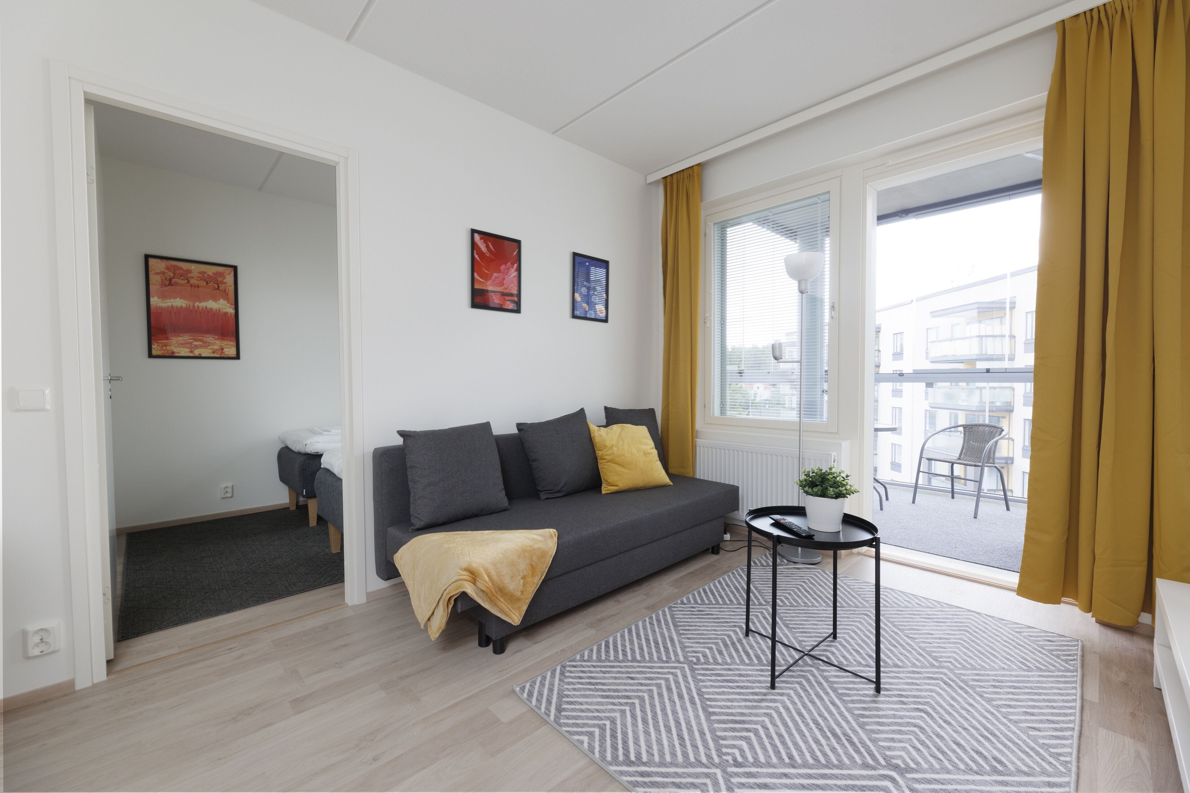 A modern living room with a grey sofa, a small table, and a window with curtains.