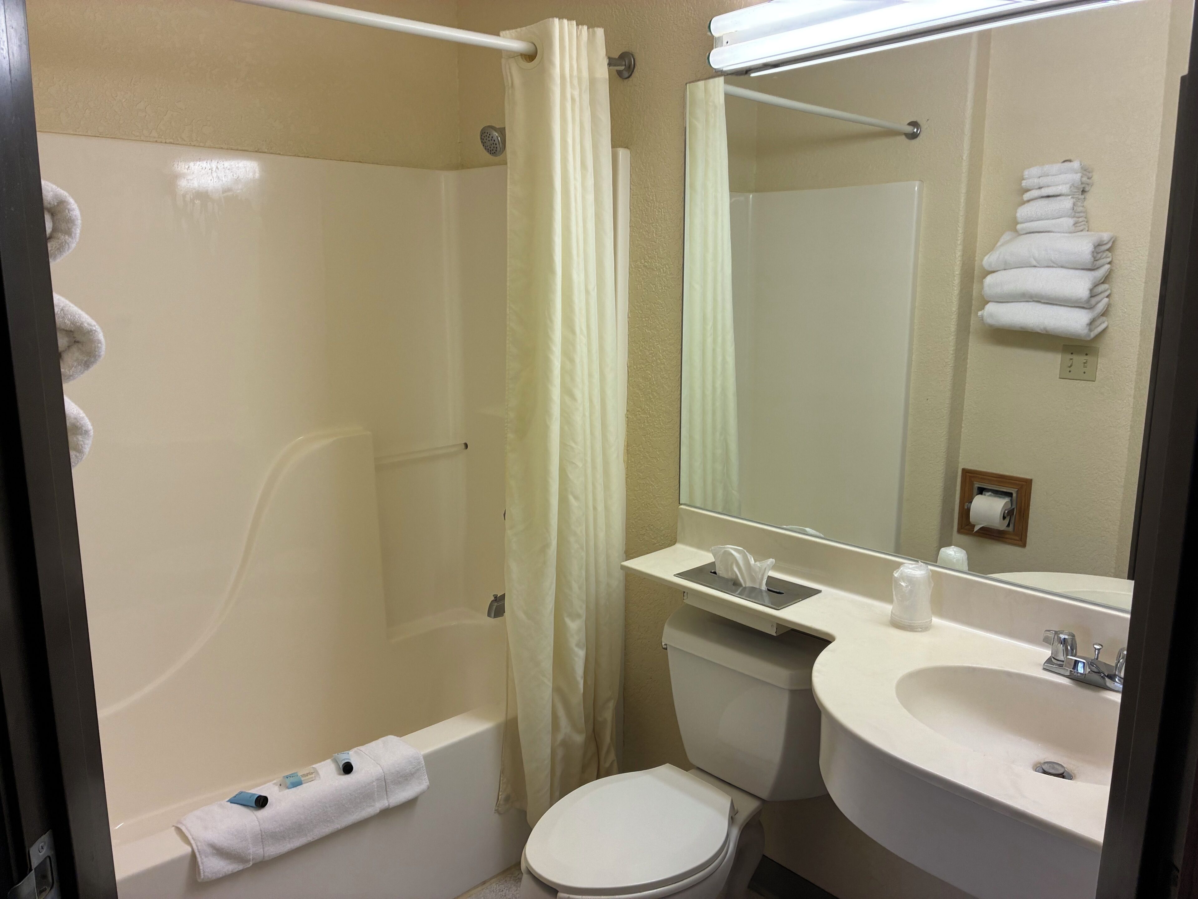 A bathroom with a bathtub, toilet, sink, and a mirror.