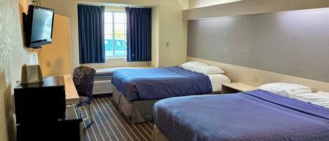 Habitación de hotel con dos camas, un televisor sobre un escritorio y una ventana con cortinas.