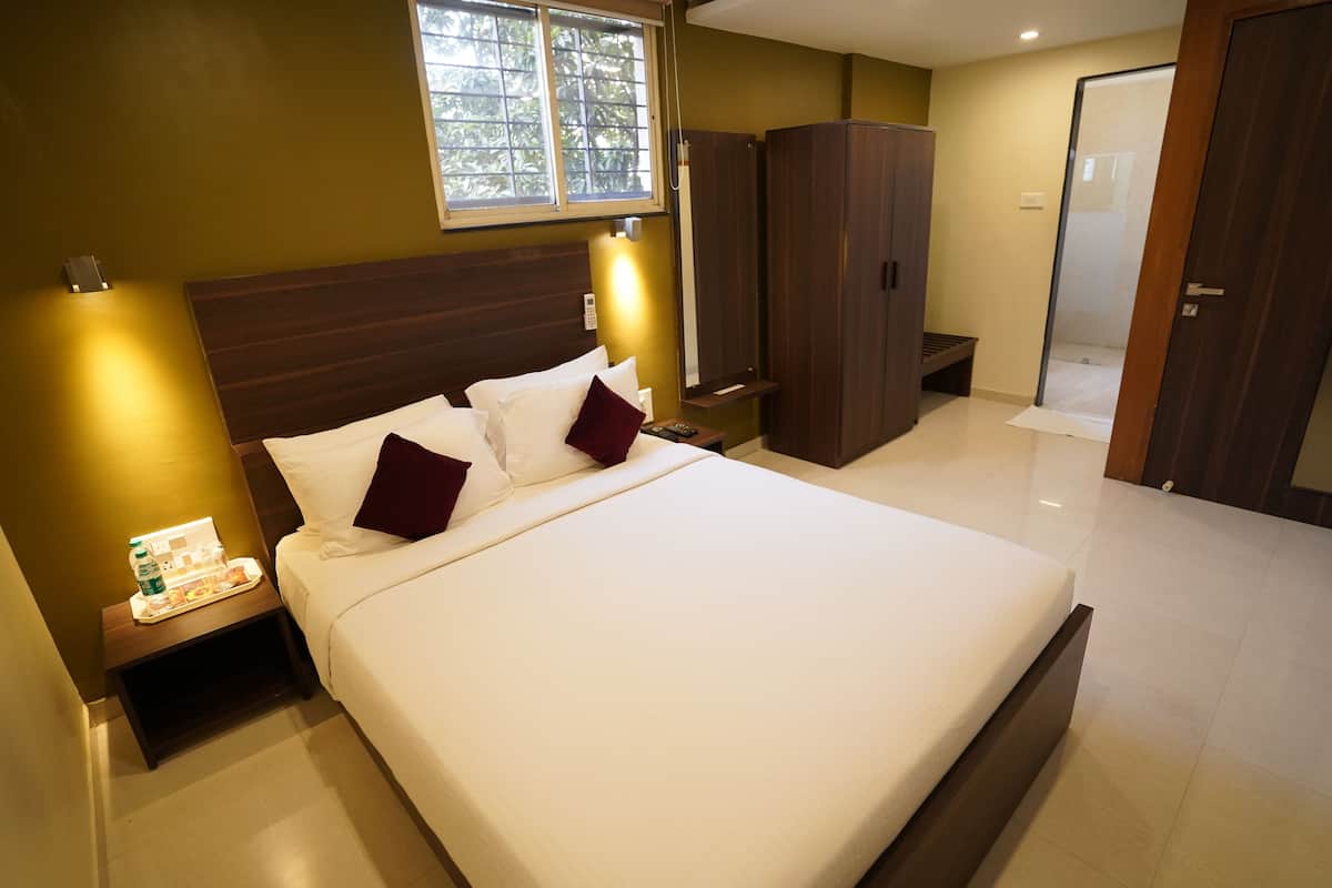 Habitación de hotel con una cama grande, una mesita de noche con un bandeja de desayuno, un armario y un espejo.