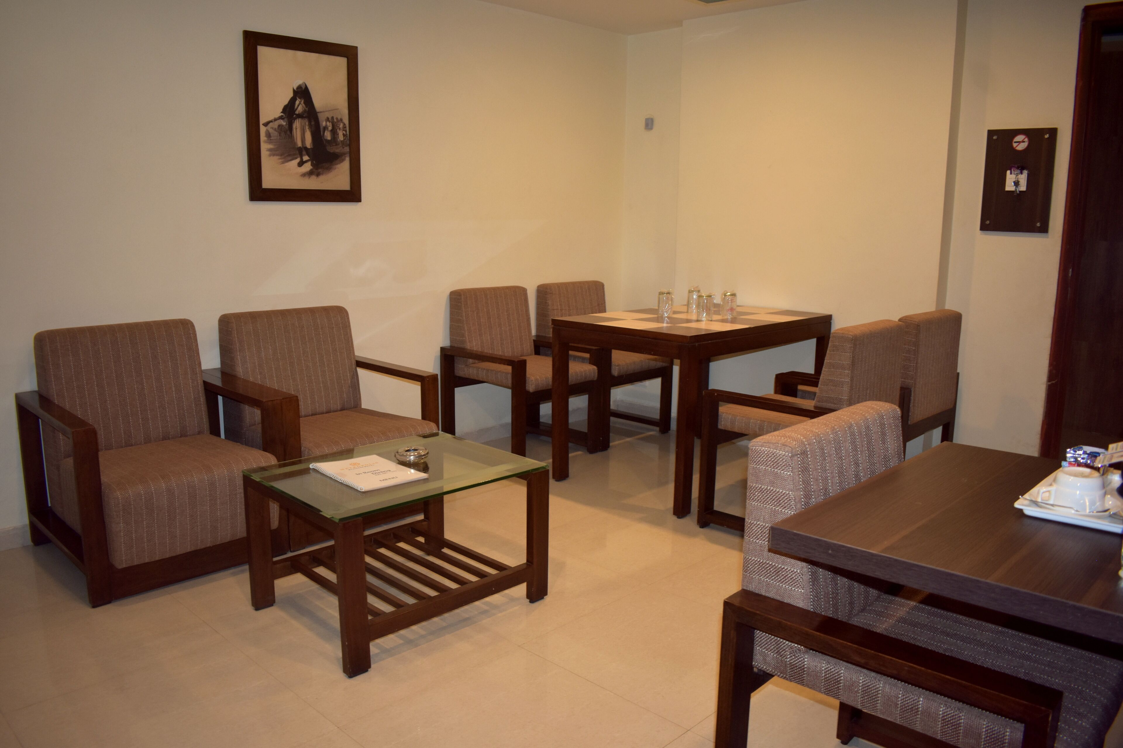 A room with six wooden chairs and two glass-top tables, arranged in a U-shape.