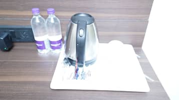 Una tetera sobre un posavasos, con dos botellas de agua al fondo.