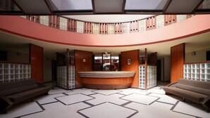 A spacious lobby with a curved reception desk, two sofas, and a patterned floor. - Metropolis Hotel (Hubli)