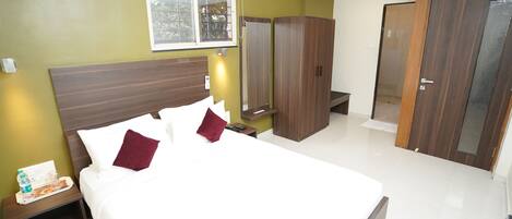 A hotel room with a large bed, a nightstand, a wardrobe, and a mirror.