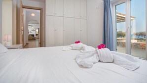 A hotel room with a large bed, a wardrobe, and a balcony with a view. - SEASIDE VILLA MARIA (PAROS)