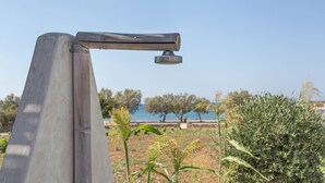 A metal structure with a water spout, set against a backdrop of trees and a clear sky. - SEASIDE VILLA MARIA (PAROS)