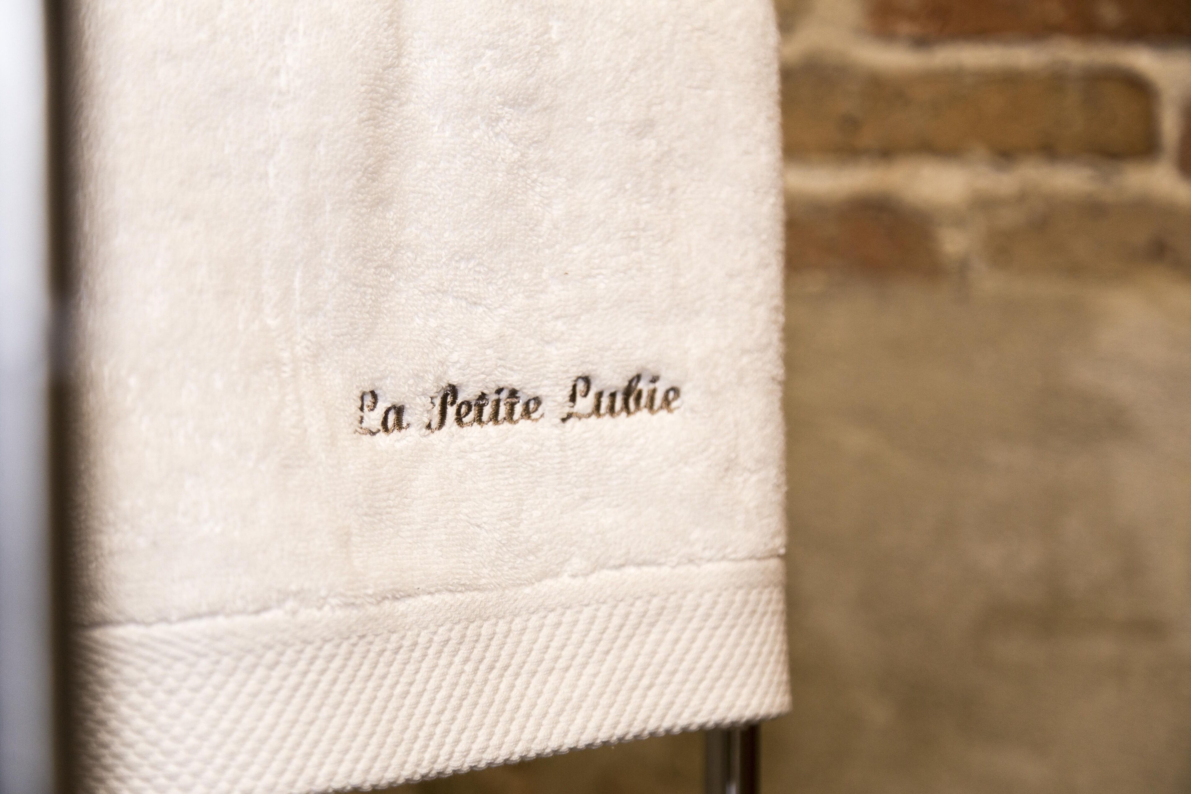 Una toalla de tela blanca con el texto bordado "La Petite Louise".