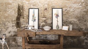 Una mesa de madera rústica con obras de arte enmarcadas, una escultura decorativa de un caballo y una pequeña estantería.