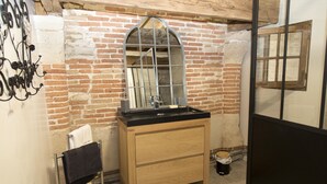 Un baño con tocador de madera, espejo y lavamanos negro.