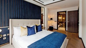 A modern hotel room with a large bed, a bedside table, a lamp, and a wardrobe. - 3-bed Deluxe 517 (London)