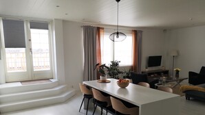 Ein modernes Wohnzimmer mit Essbereich, Fernseher und Balkon mit Blick.
