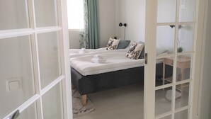 Ein Schlafzimmer mit Bett, Nachttischen, Schreibtisch und einem Fenster mit Vorhängen.