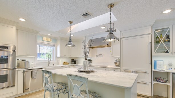 A modern kitchen with white cabinetry, stainless steel appliances, and a central island with bar stools. - Luxe Jupiter Home w/ Pool House, Near Golf & Beach (Jupiter)