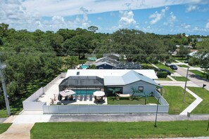 Ein Wohnhaus mit Swimmingpool, Sitzgelegenheiten im Freien und einem umzäunten Garten.