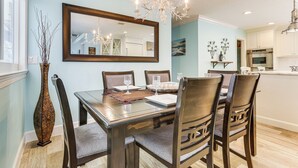 A dining area with a wooden table, chairs, and a chandelier. - Luxe Jupiter Home w/ Pool House, Near Golf & Beach (Jupiter)