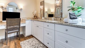 A bathroom with a wooden chair, white cabinets, a large mirror, and a plant. - Luxe Jupiter Home w/ Pool House, Near Golf & Beach (Jupiter)