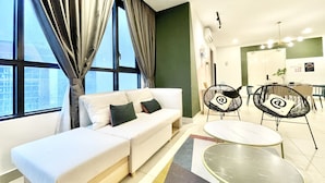 A modern living room with a sofa, two armchairs, a coffee table, and large windows with curtains. - KL Gateway Premium Residences by MOKA (Kuala Lumpur)