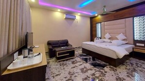 Een moderne hotelkamer met een bed, een bank, een televisie en een bureau met toiletartikelen.