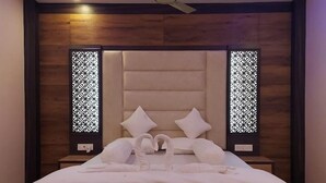 Een hotelkamer met een groot bed, twee nachtkastjes, een plafondventilator en decoratieve schermen aan de wanden.