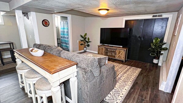 A living room with a sofa, a coffee table, a TV, and a potted plant.