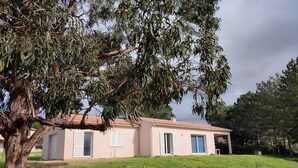 A two-story house with a tiled roof, surrounded by a grassy area and trees. - New individual villa in Southern Corsica. (Sartène)