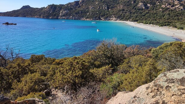A coastal landscape with a clear blue sea, a sandy beach, and a rocky mountain backdrop. - New individual villa in Southern Corsica. (Sartène)