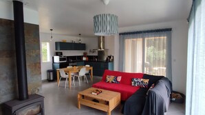 A modern living room with a fireplace, a dining area, and a kitchen. - New individual villa in Southern Corsica. (Sartène)