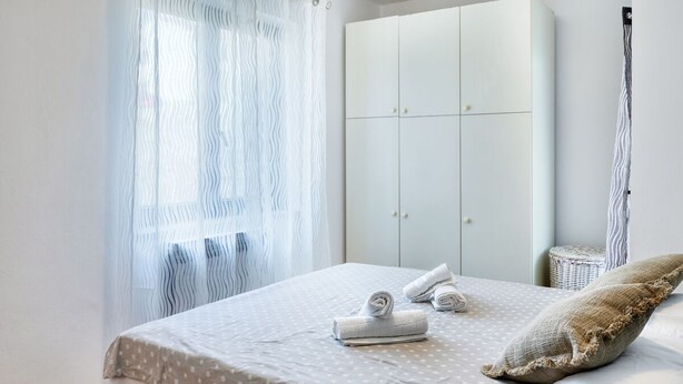 A bedroom with a bed, a wardrobe, and a window with sheer curtains. - House Viola (Pula)