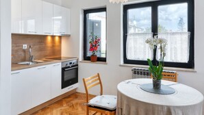A modern kitchen with white cabinets, a wooden countertop, and a dining area with a table and chairs. - House Viola (Pula)