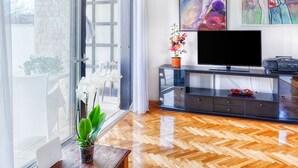 A modern living room with a large window, a flat-screen TV, a potted plant, and artwork on the wall. - House Viola (Pula)