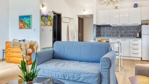 A modern living room with a blue checkered sofa, a wooden cabinet, and a glass coffee table with orchids. - House Viola (Pula)