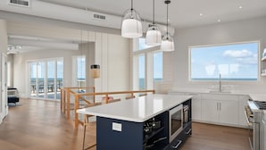 Una cucina moderna con isola centrale, ampie finestre e vista sull'oceano.