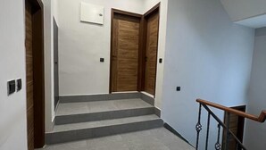 A staircase with a handrail, leading to a landing with two wooden doors. - The Dream House (New Delhi)