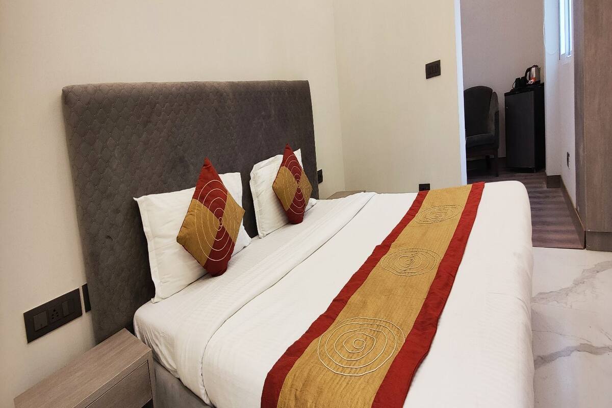 Una habitación de hotel con una cama, dos almohadas, una mesita de noche y un cabecero.