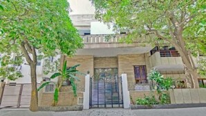 A two-story residential building with a gated entrance, a small balcony on the upper floor, and potted plants around the entrance. - The Dream House (New Delhi)