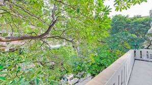 A balcony with a view of dense foliage and a building in the background. - The Dream House (New Delhi)