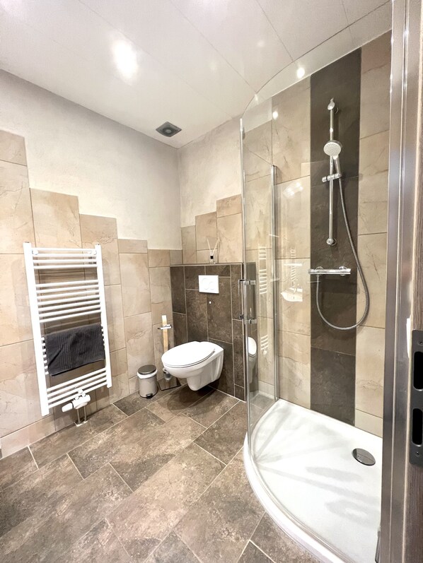 Un baño moderno con ducha acristalada, inodoro blanco y un perchero para toallas.