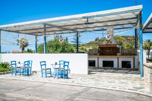 Un área de estar al aire libre con sillas azules y un porche cubierto.