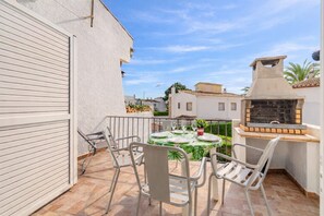 A patio with a table set for two, outdoor seating, and a barbecue grill.