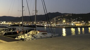 A marina with boats docked, a clear sky, and a cityscape in the background.
