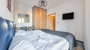 Une chambre d’hôtel comprenant un lit, un bureau, une chaise, une télévision et une armoire en bois.