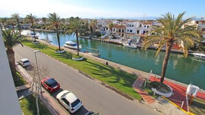 A marina with boats, a road with cars, and palm trees.