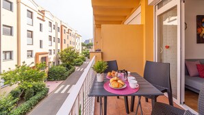 A balcony with a table set for breakfast, surrounded by buildings.