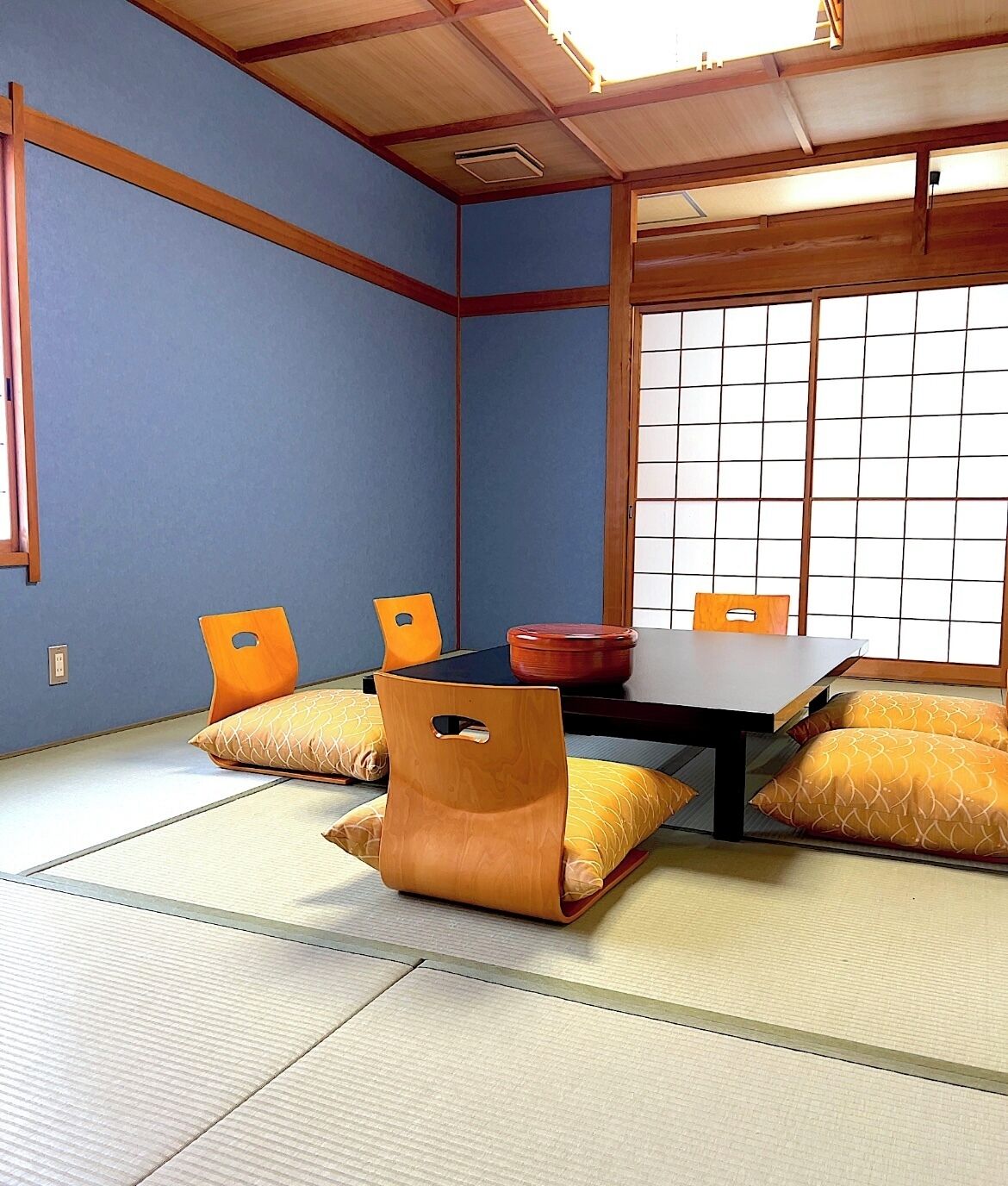 Een kamer met tatami matten, een lage tafel, twee stoelen en een shoji scherm.