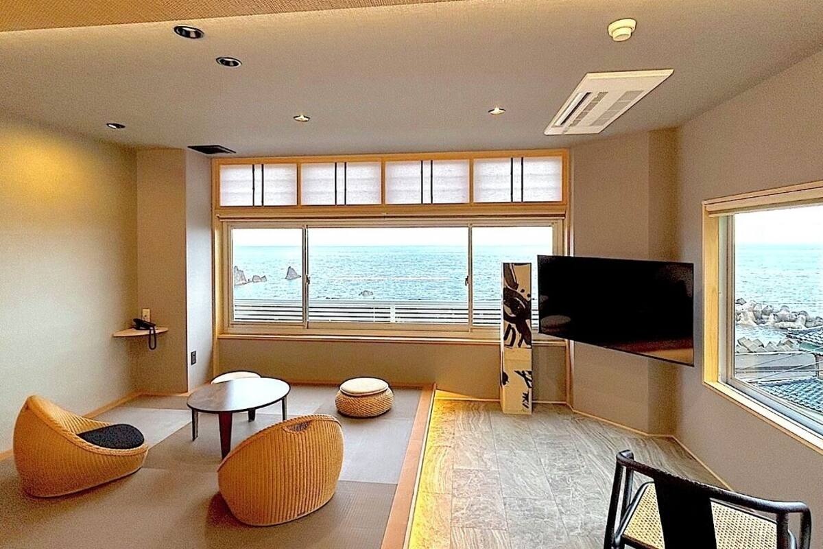 Ein modernes Zimmer mit großem Fenster, einem Flachbildfernseher und einer Sitzecke mit Tisch und Stühlen.