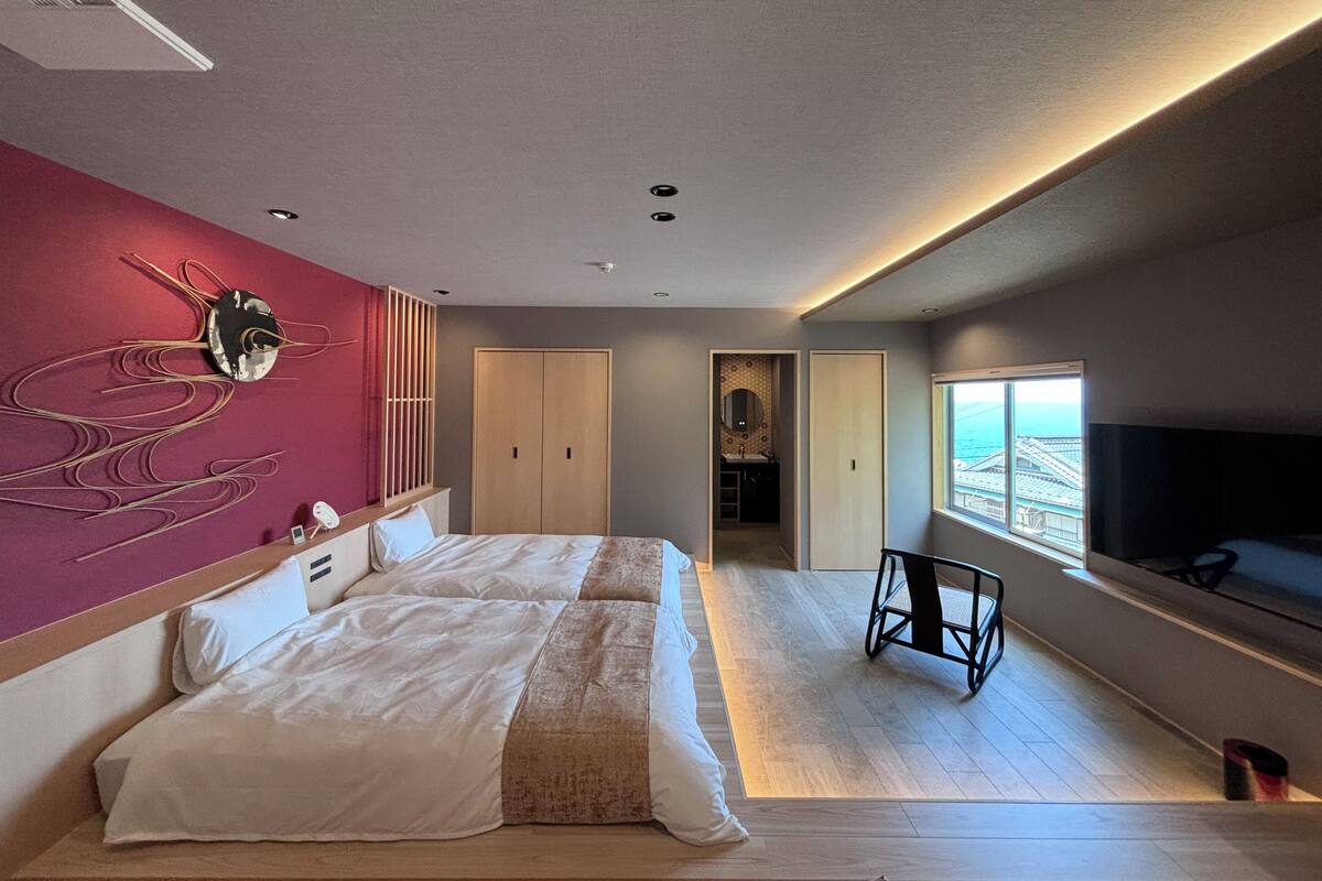 Ein modernes Hotelzimmer mit einem großen Bett, einem Fernseher und Blick auf die Stadt.