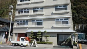 A multi-story building with a flat facade, multiple balconies, and a garage entrance. - Ryori Ryokan Kanetomo (Echizen)