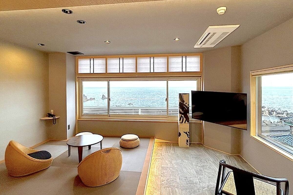 Ein modernes Wohnzimmer mit großem Fenster, einem Flachbildfernseher und Meerblick.