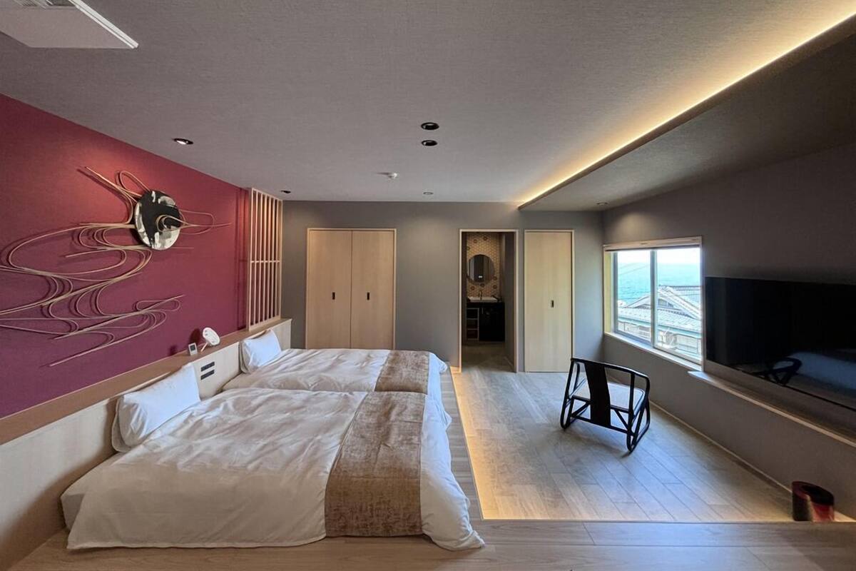 Ein modernes Hotelzimmer mit einem großen Bett, einem Fernseher, Meerblick und einem einzigartigen Wandbild.