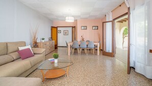 A living room with a sofa, coffee table, and a dining area with chairs and a table.